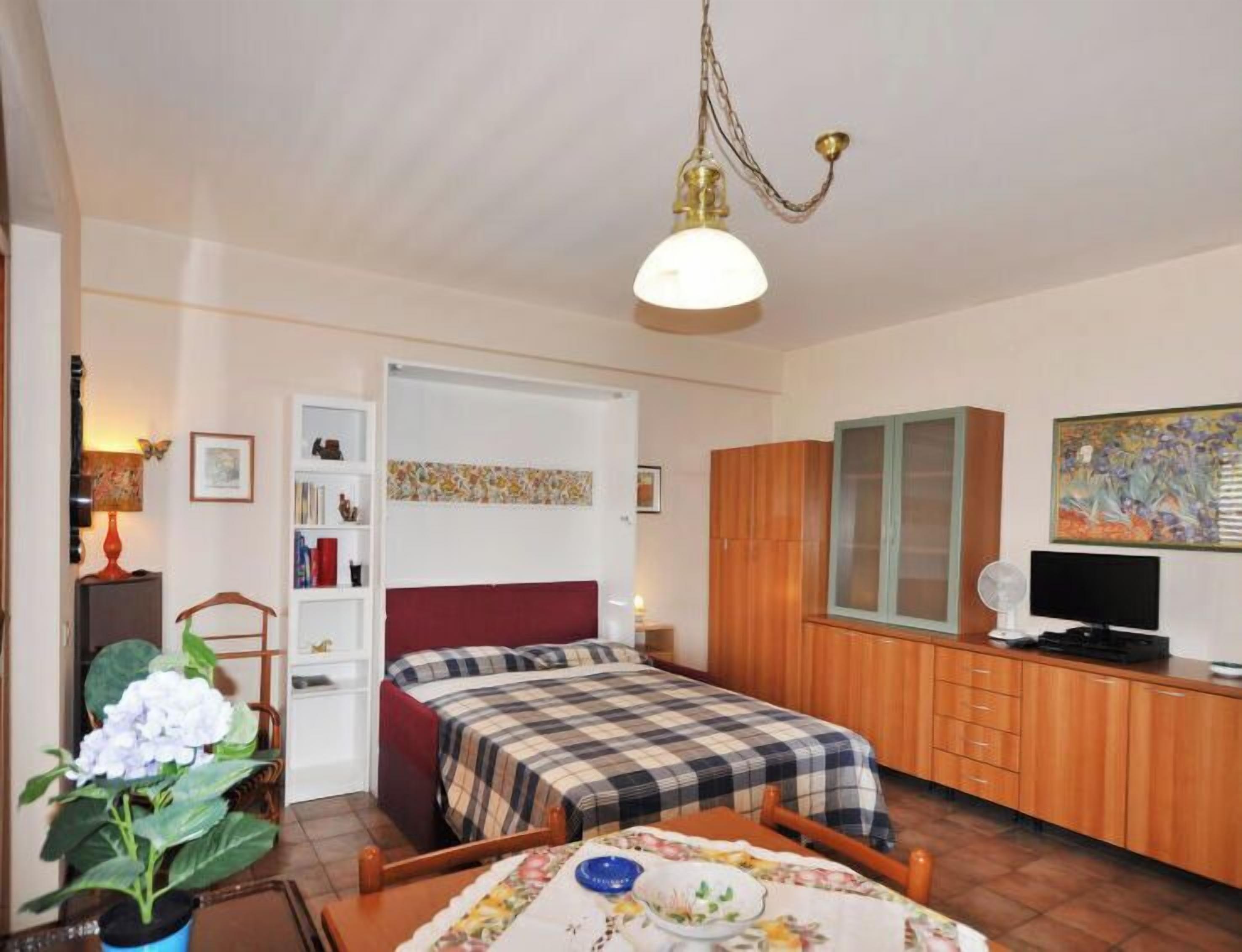 A compact bedroom with a bed, bedside table, and a small desk with a chair.