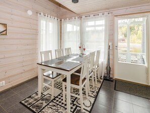 Un comedor con una mesa y sillas de madera, una alfombra estampada y vistas a un lago a través de una ventana.