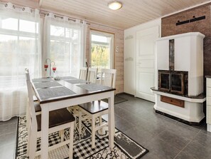 A dining area with a table and chairs, a fireplace, and a view through a window. - Pentintupa by Interhome (Joensuu)