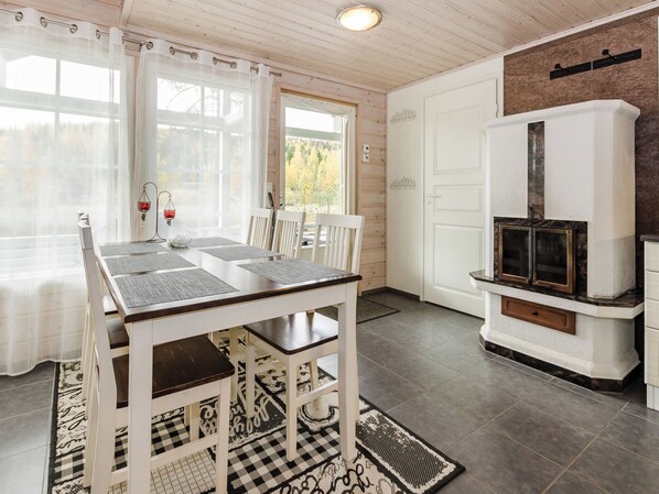 A dining area with a table and chairs, a fireplace, and a view through a window.