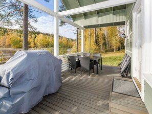 Una terraza techada al aire libre con una parrilla, una mesa de comedor y sillas.