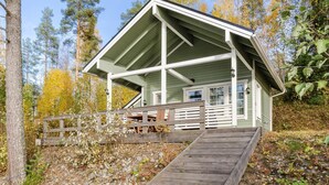 A cabin with a wooden deck and a staircase leading to the entrance.