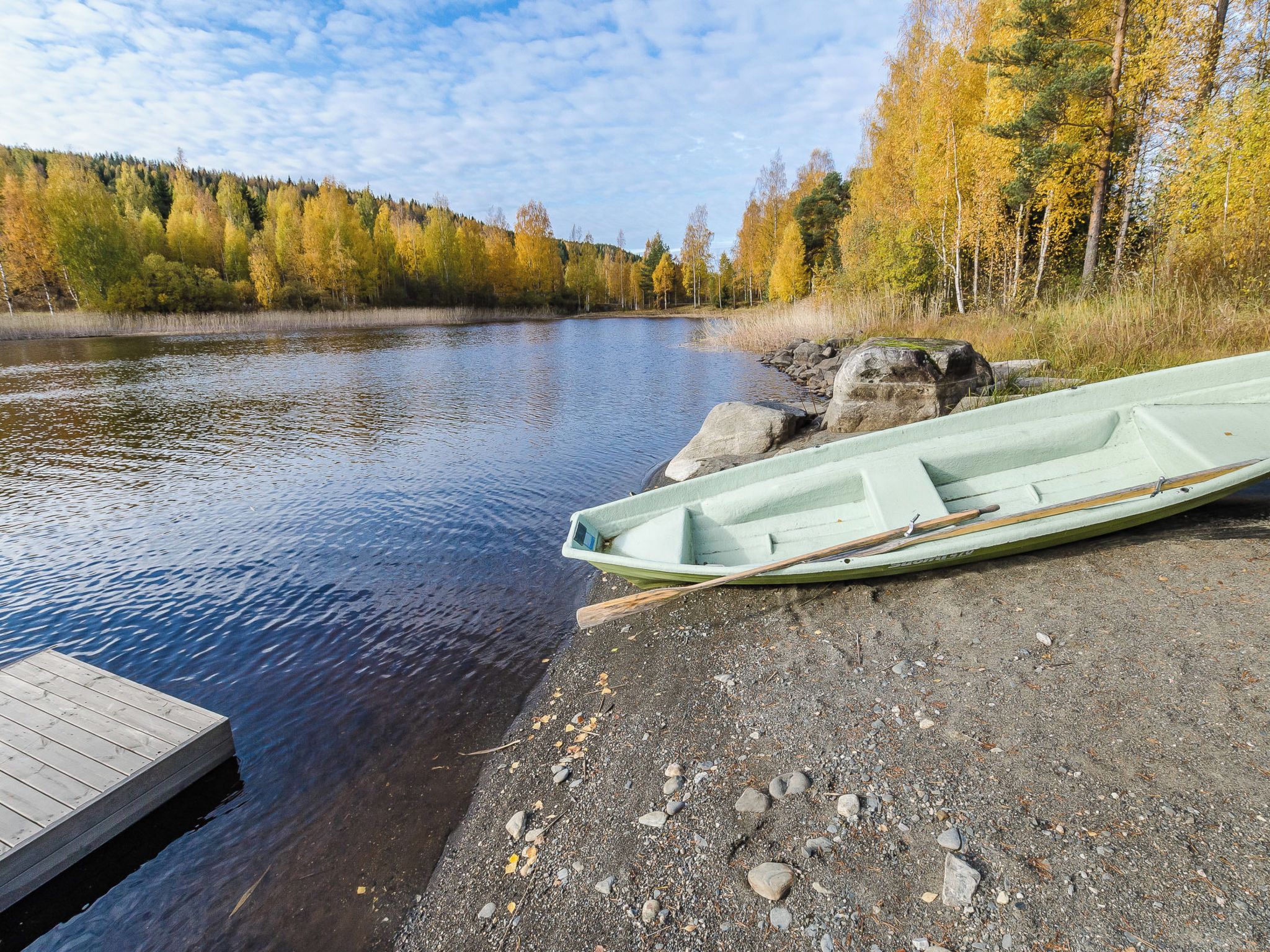 Une rivière paisible, avec un quai et un bateau à rames.