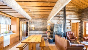 Ein rustikales Blockhaus-Interieur mit Holztisch, einer Couch und einem Kamin.