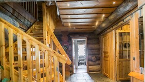Eine Holztreppe führt zu einem Raum mit Steinboden, Holzwänden und einer Tür mit Glasscheiben.