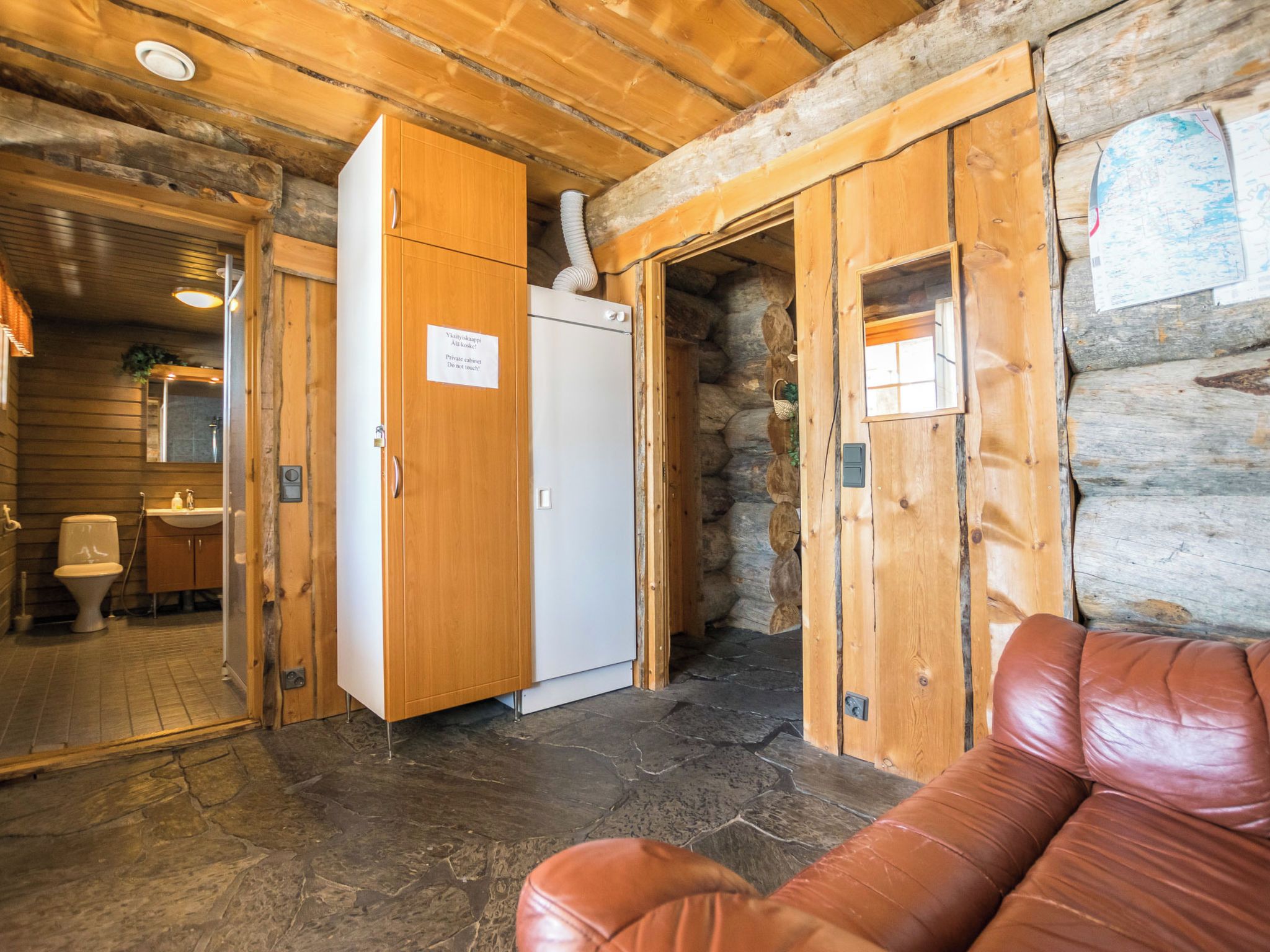 Un interior de madera con sauna, un armario privado y suelo de piedra.