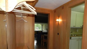 Ein Flur mit Holzwänden, einer Sitzbank, einem Kleiderständer und einem Küchenbereich mit Schränken und einem Spülbecken.