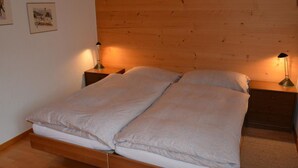 Ein Doppelbett mit zwei Nachttischen, jeweils mit einer Lampe, in einem Zimmer mit Holzwänden und Holzböden.