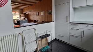 Eine moderne Küche mit weißen Schränken, einer schwarzen Arbeitsplatte und einer Holzbalkendecke.