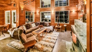 A log cabin interior with a cozy living area featuring a sofa, armchairs, a fireplace, and large windows. - Arctic chalet by Interhome (Ylläsjärvi)