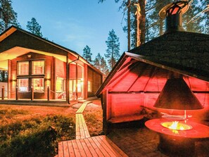 A cabin with a large glass window section, a wooden deck, and a chimney. - Arctic chalet by Interhome (Ylläsjärvi)