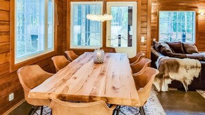A wooden interior with a dining table, chairs, a sofa, and large windows. - Arctic chalet by Interhome (Ylläsjärvi)