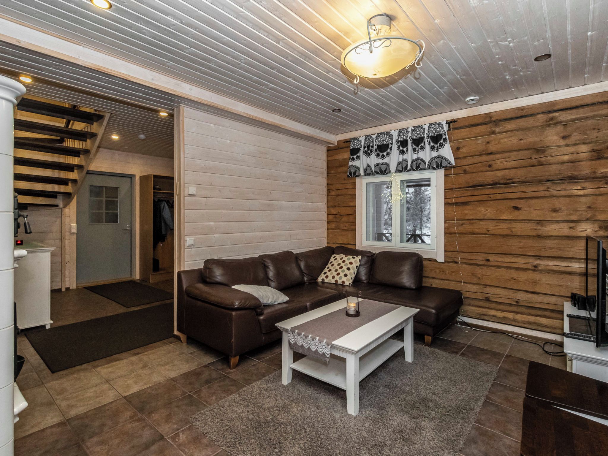 Una sala acogedora con un sofá de cuero marrón, una mesa de centro blanca y un revestimiento de madera.