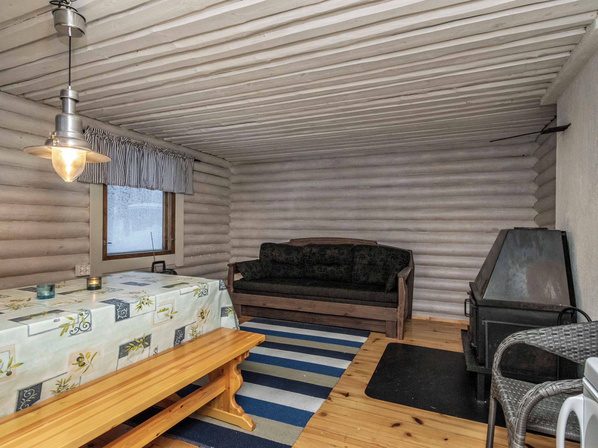 Una habitación tipo cabaña de troncos con una cama, un sofá, un televisor y una chimenea.