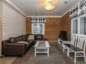 A cozy room with a brown leather sofa, a white coffee table, and a TV stand.