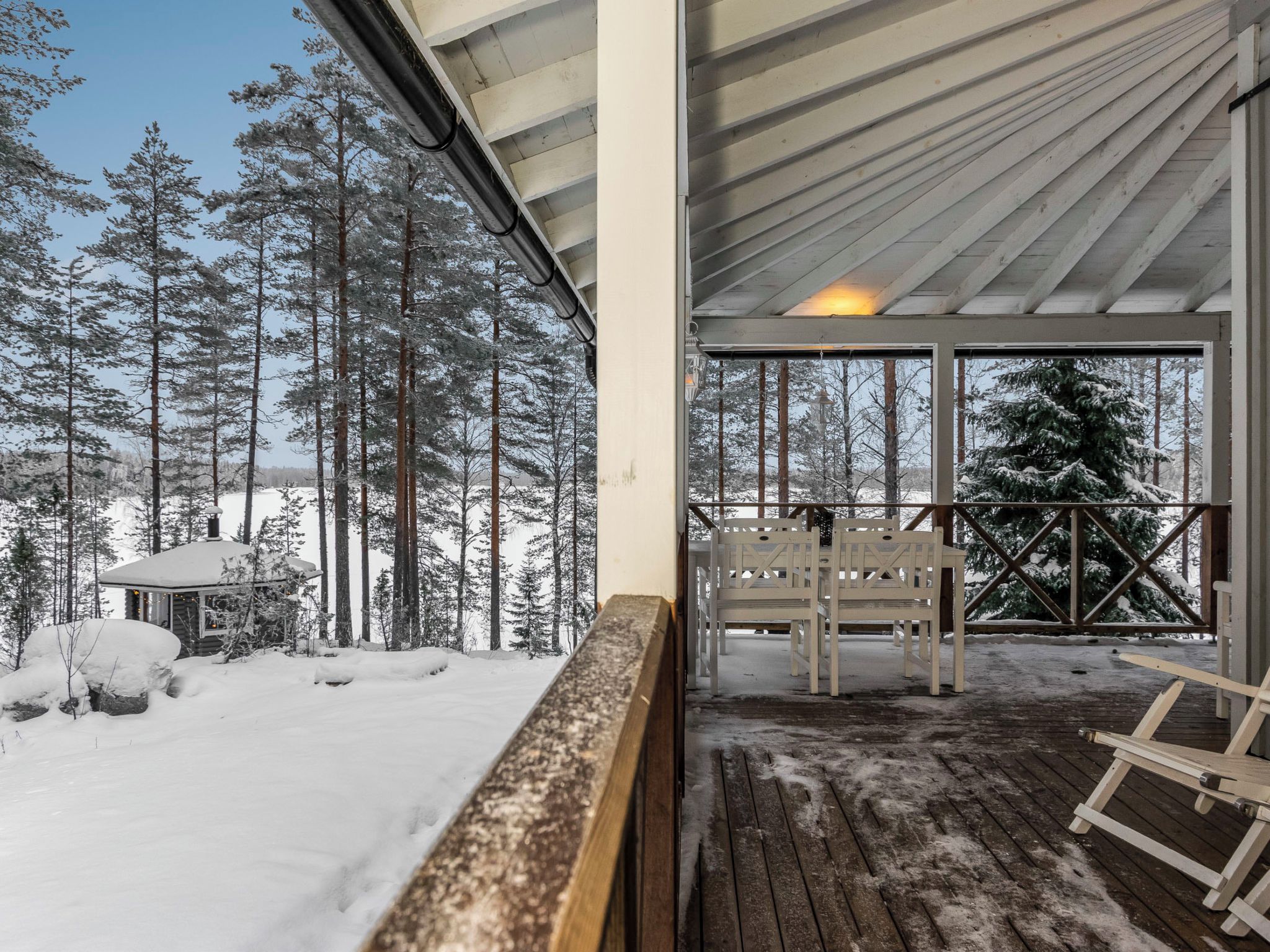 Une terrasse en bois avec des bancs, un paysage enneigé et un chalet en arrière-plan.
