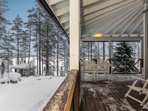 Une terrasse en bois avec des bancs, un paysage enneigé et un chalet en arrière-plan.