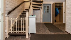 Interior de madera con una escalera, una puerta y un perchero.