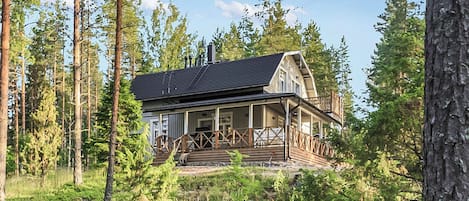 A cabin with a porch, surrounded by forest.
