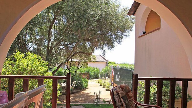 Zona de terrassa coberta amb vistes a un jardí i un camí que condueix a un edifici.
