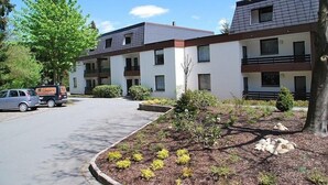 Un immeuble d’appartements moderne doté d’un espace de stationnement et d’un jardin aménagé.