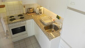 Una cocina compacta con estufa, horno, pileta y una pequeña zona de encimera.