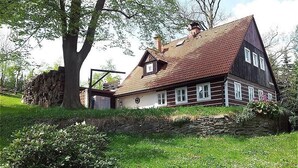 Ein traditionelles Haus mit steilem Dach, einer Steinmauer und einem gepflegten Garten.