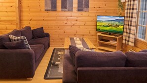 A cozy log cabin interior with two purple sofas, a wooden coffee table, and a flat-screen TV on a wooden stand. - Rukan vaarala 2 c 3 by Interhome (Kuusamo)