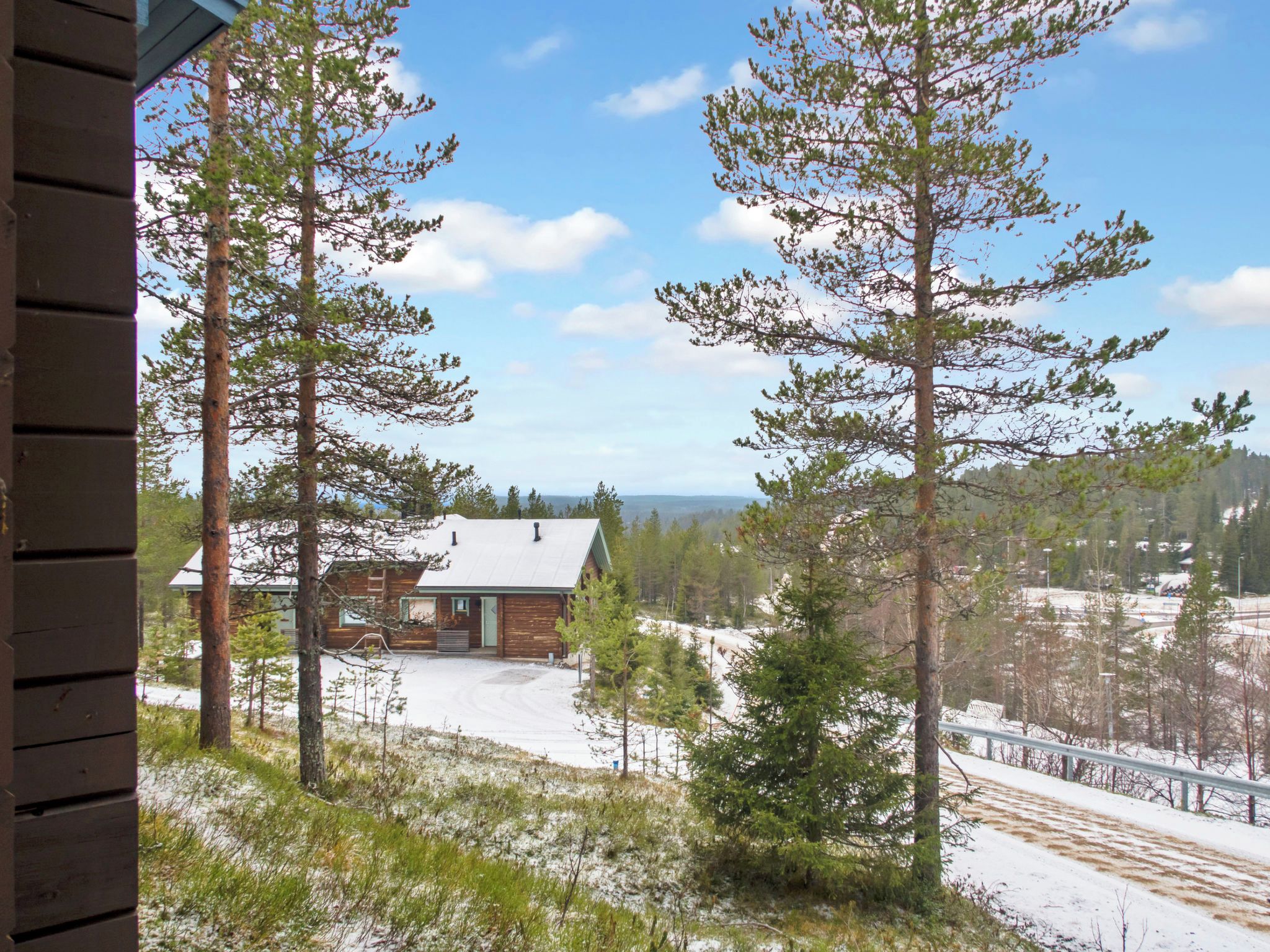 A cabin with a wooden exterior, surrounded by snow-covered ground and trees.