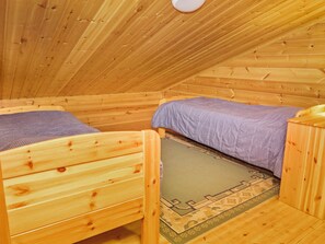 A wooden cabin room with two beds, a small table, and a ceiling light. - Rukan vaarala 2 c 3 by Interhome (Kuusamo)