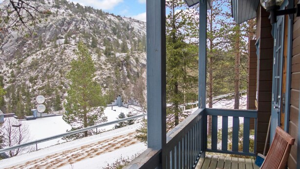 A wooden porch with a bench, overlooking a snowy landscape with trees and a mountain in the background. - Rukan vaarala 2 c 3 by Interhome (Kuusamo)