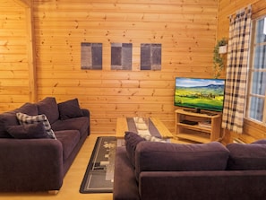 A cozy log cabin interior with a sofa set, a flat-screen TV, and a wooden wall with artwork. - Rukan vaarala 2 c 3 by Interhome (Kuusamo)