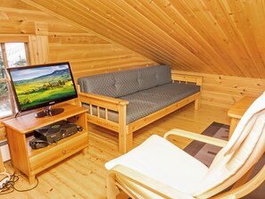 A cozy wooden cabin with a sofa, a television, and a chair. - Rukan vaarala 2 c 3 by Interhome (Kuusamo)