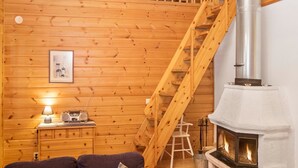 A cozy cabin interior with a wooden interior, a fireplace, a staircase, and a radio on a dresser. - Rukan vaarala 2 c 3 by Interhome (Kuusamo)