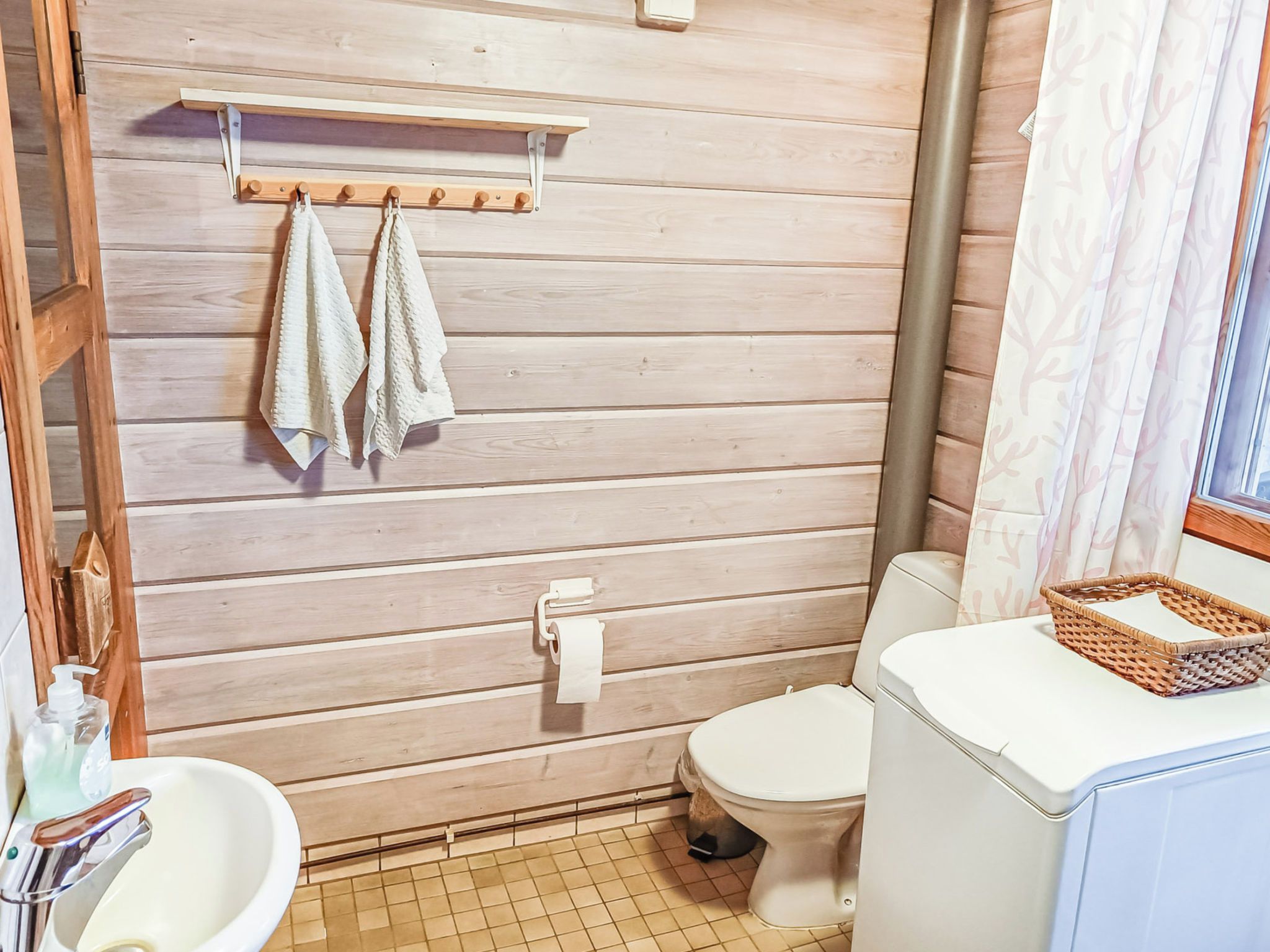 Un baño con pared de madera, un inodoro, un lavabo y un estante con toallas.