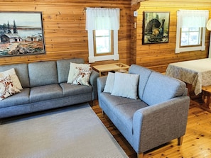 A cozy cabin interior with two sofas, a small table, and wooden walls.