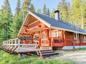 Une cabane en bois avec une véranda, une cheminée et une terrasse.