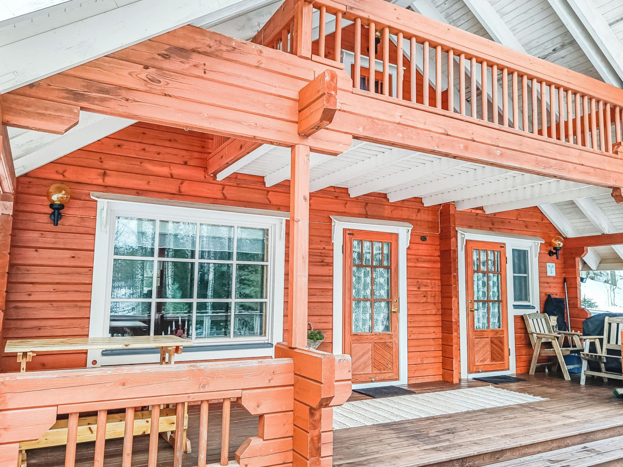 A wooden cabin with a porch, two doors, and a bench.
