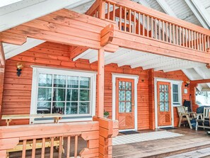 A wooden cabin with a porch, two doors, and a bench.