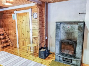 A wooden interior with a fireplace, a door, a chair, and a bag on the floor.