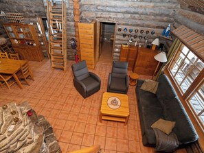 A log cabin interior with a dining area, seating, a fireplace, and a collection of hats on the wall. - Luminalle by Interhome (Kuusamo)