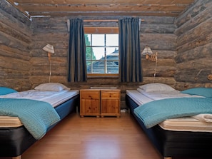 A log cabin bedroom with two beds, a wooden dresser, and a window with curtains. - Luminalle by Interhome (Kuusamo)