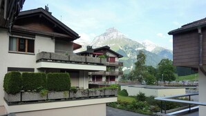 Ein mehrstöckiges Gebäude mit Balkonen, Blick auf die Berge und einem Parkplatz.