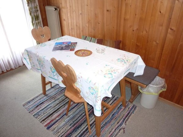 A dining table with a floral tablecloth, wooden chairs, and a small rug on the floor. - Steinacher Appartement/Fewo 5-Bettwohnung by Interhome (Engelberg)