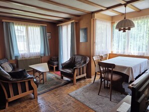 A cozy room with a wooden floor, a table with chairs, a sofa, a leather chair, and a radiator. - Steinacher Appartement/Fewo 5-Bettwohnung by Interhome (Engelberg)