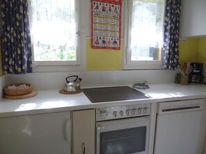 A kitchen with a stove, a kettle, and a coffee maker.