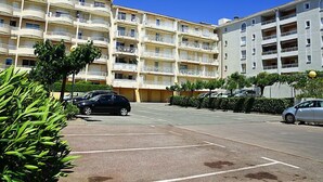 Et hotel med flere etager, altaner, parkeringsplads og grøn bevoksning.