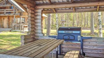 A wooden outdoor patio with a barbecue grill and a table.