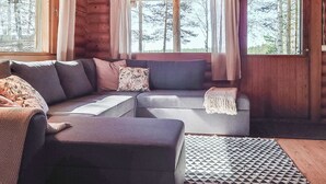 Interior acolhedor de uma cabana com um sofá modular, uma mesa pequena e um tapete estampado.