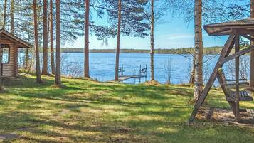 Mökki, jonka laiturilta on kulku järveen, ja jonka ympärillä on puita.
